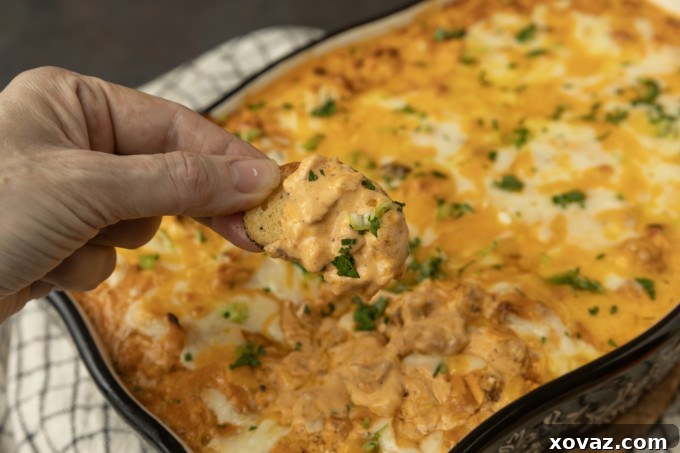 Buffalo chicken dip with a hand dipping a chip.