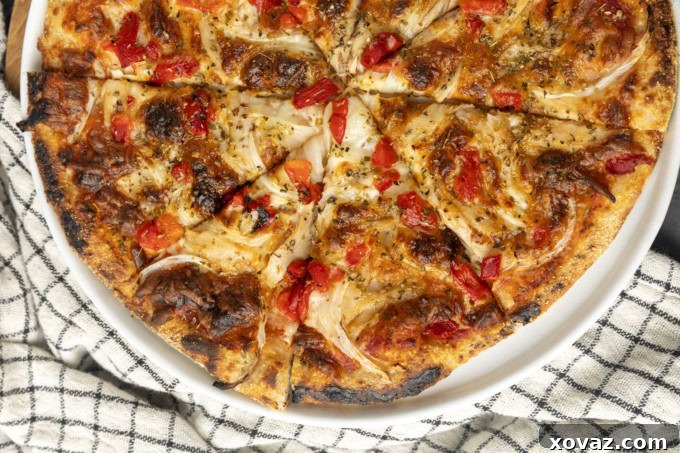 Tuna pizza dough topped with sauce, cheese, onions, and red peppers before baking