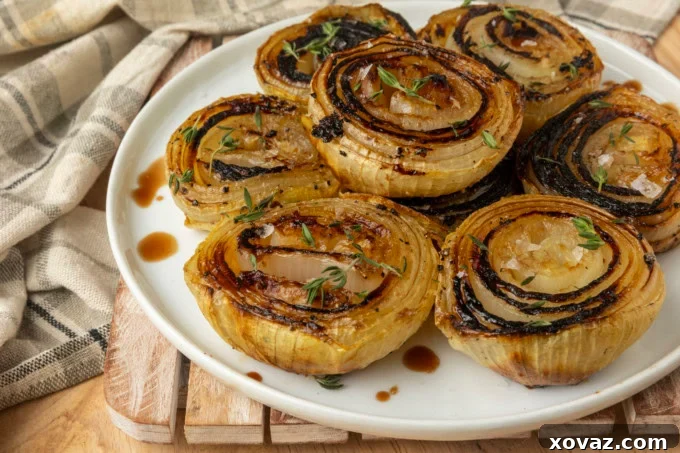 Baked onions with a rich golden-brown exterior on a white plate.