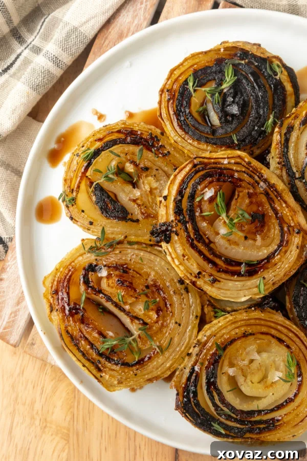 A close-up of tender baked onions on a plate, garnished with fresh herbs.