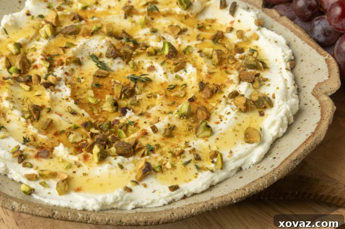 whipped goat cheese appetizer in a pottery bowl with crostini, salami, and grapes