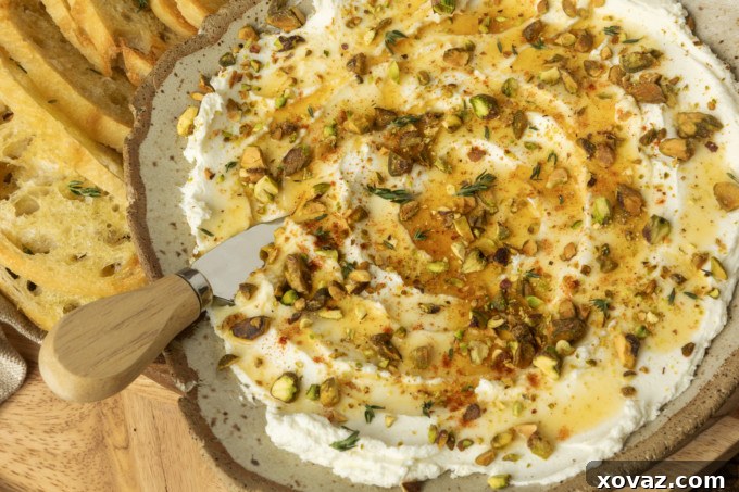 whipped goat cheese appetizer in a pottery bowl with crostini, salami, and grapes