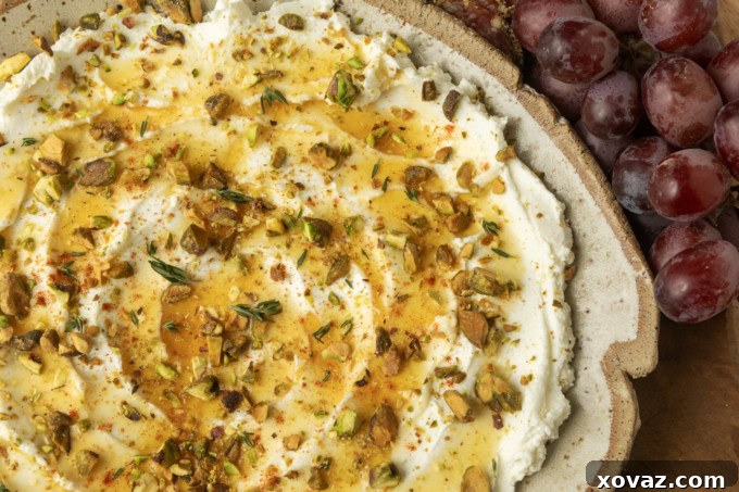 whipped goat cheese appetizer in a pottery bowl with crostini, salami, and grapes