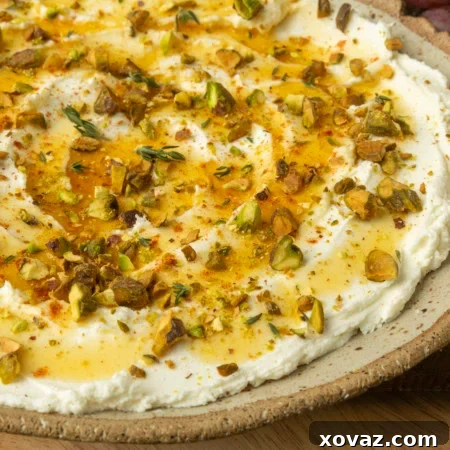 whipped goat cheese appetizer in a pottery bowl with crostini, salami, and grapes