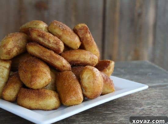 Golden brown cinnamon sugar soft pretzel bites piled high on a white dish, ready to be enjoyed.