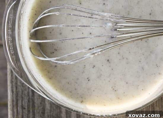 cinnamonrollonstick3 A child's hand dipping a cinnamon roll on a stick into a bowl of vanilla bean glaze.