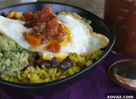 Close-up of a Tex Mex Rice Bowl with a perfectly fried egg, ready to be eaten with a spoon.
