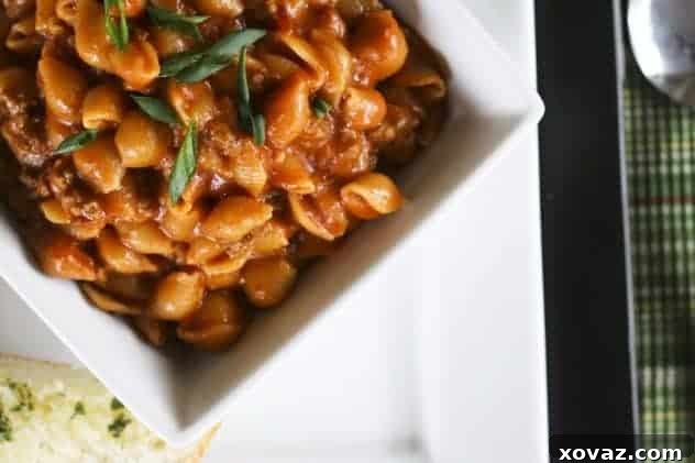 A closer view of Bacon Cheeseburger Pasta in a white bowl, garnished with green onions.