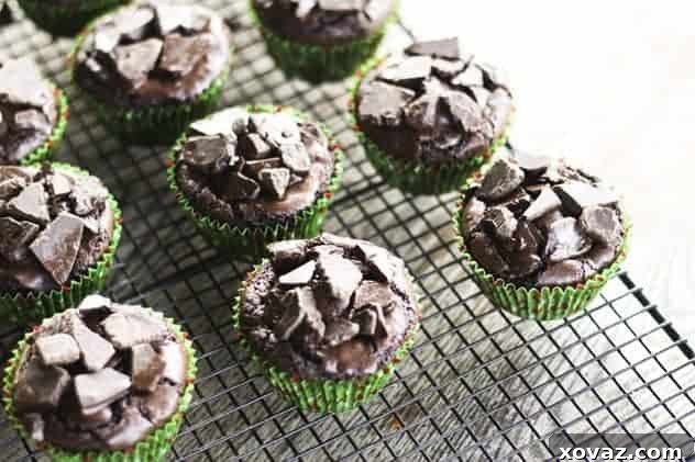 Warm brownie cupcakes topped with melting dark chocolate chunks being spread.