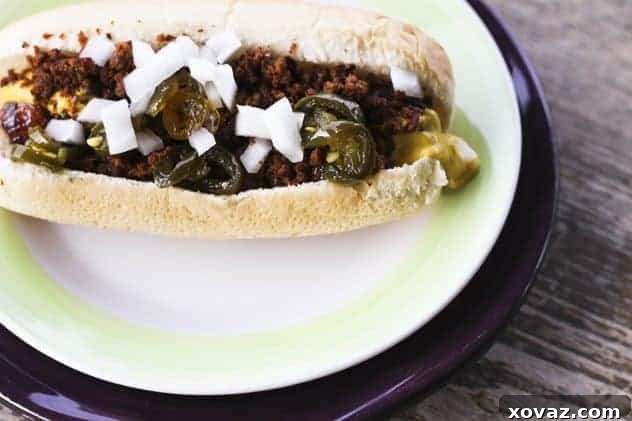 A top-down view of a fully dressed crispy chorizo dog with mustard, onions, and jalapenos.