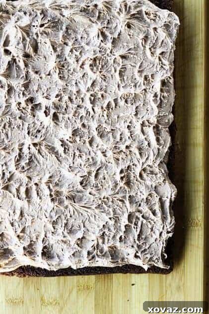 A slice of frosted brownie cake, showing the thick Nutella peanut butter frosting with sea salt flakes.