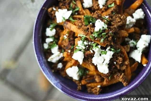 Close-up of Mexican Poutine with crispy sweet potato fries, chorizo, queso fresco, and cilantro.